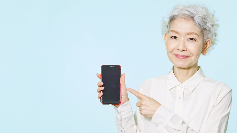 スマートフォンを指差す受付女性の写真